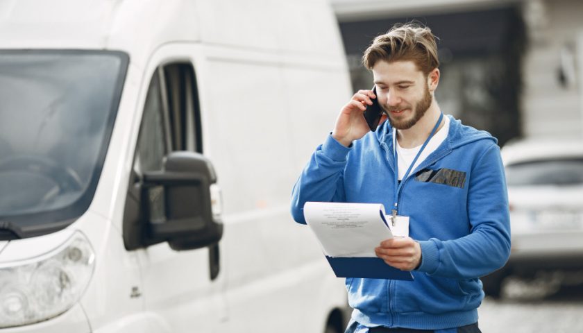 Homme au téléphone à côté de son utilitaire blanc