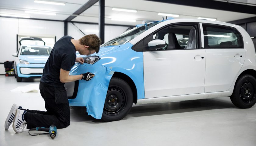 un homme appliquant de la peinture sur une voiture
