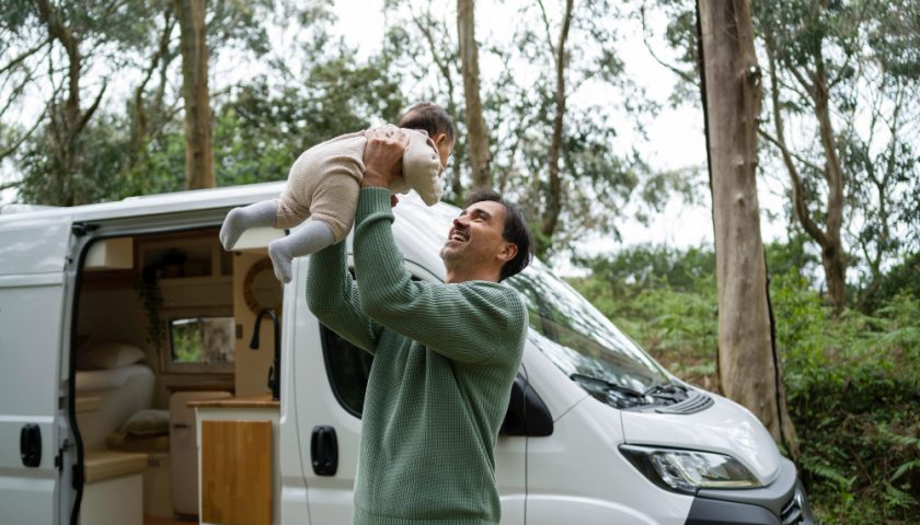 Père et son bébé devant un fourgon aménagé