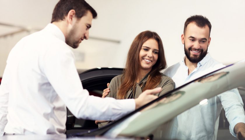 Vendeur montrant une voiture à un couple