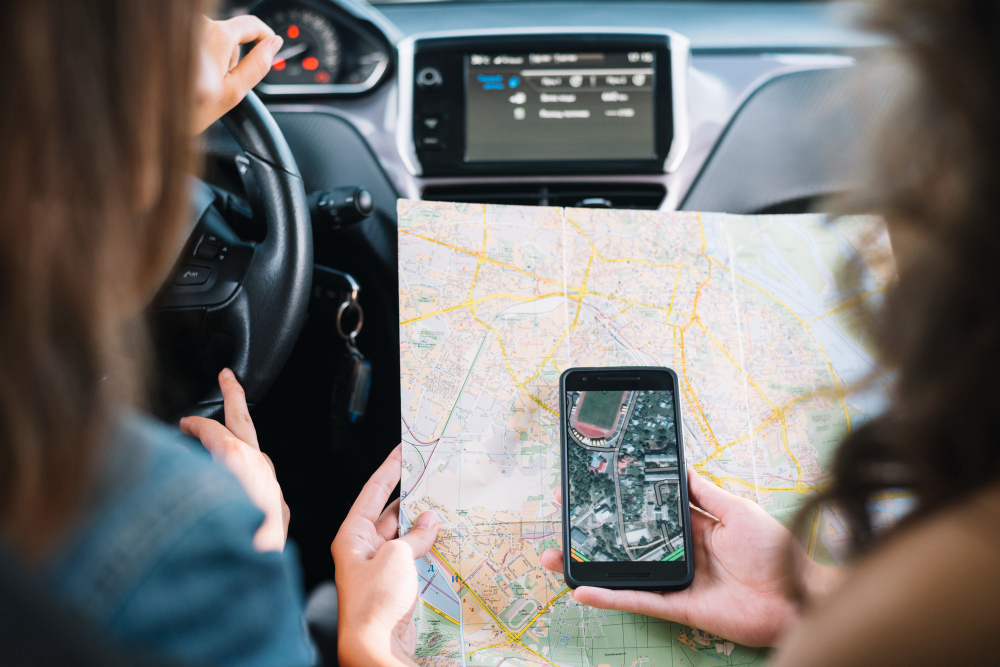 deux personnes en voiture regardant un téléphone portable et une carte de suivi
