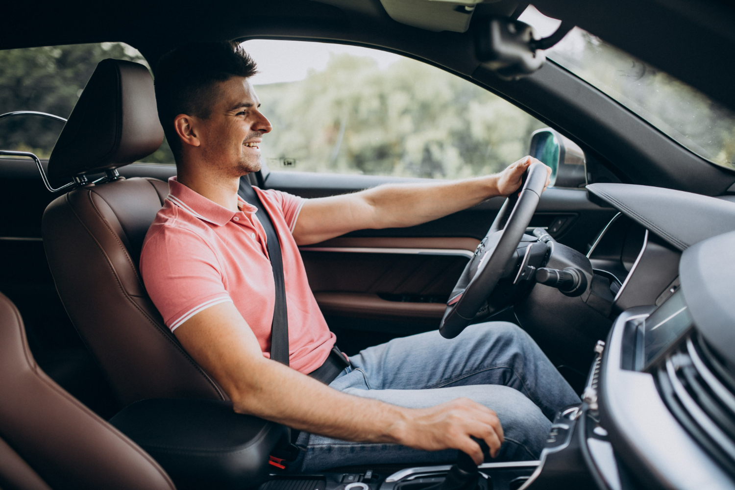 conducteur souriant la main sur le volant et l'autre sur le pommeau de vitesse