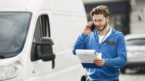 Homme au téléphone à côté de son utilitaire blanc