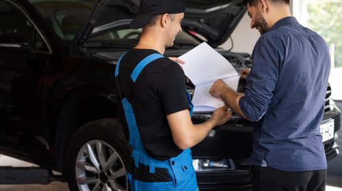 deux hommes discutant autour d'une voiture en plein entretien