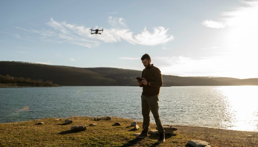 un homme faisant voler un drone au-dessus d'un lac