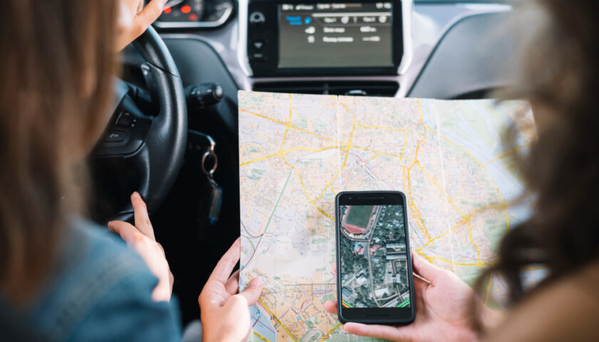 deux personnes en voiture regardant un téléphone portable et une carte de suivi